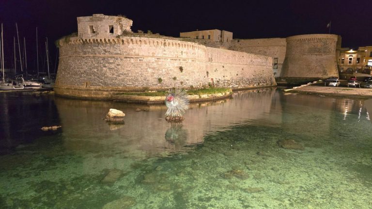 Il castello angioino di Gallipoli illuminato di notte, circondato dal mare
