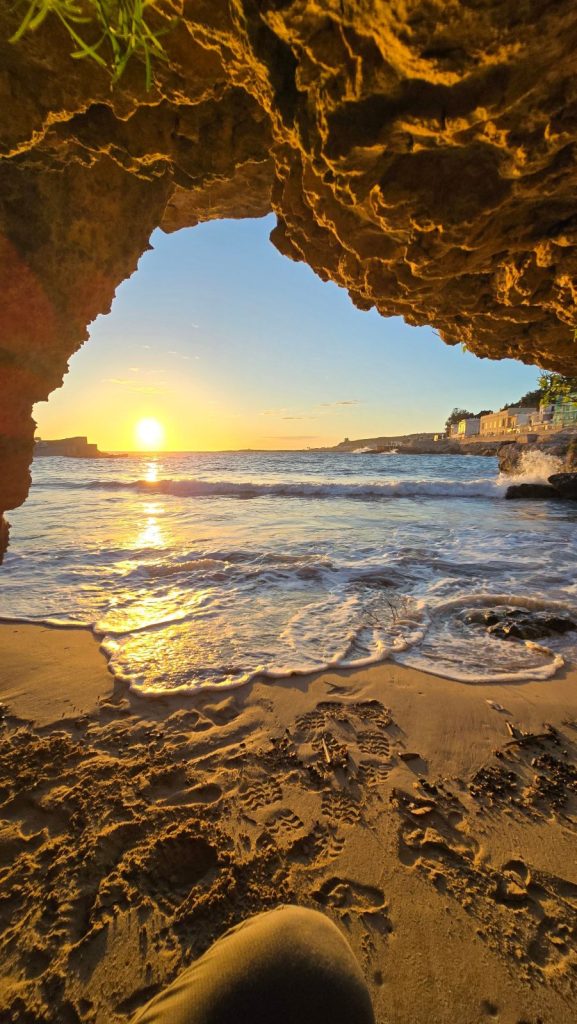 Il sole che tramonta sul mare visto dall'interno di una grotta sulla spiaggia